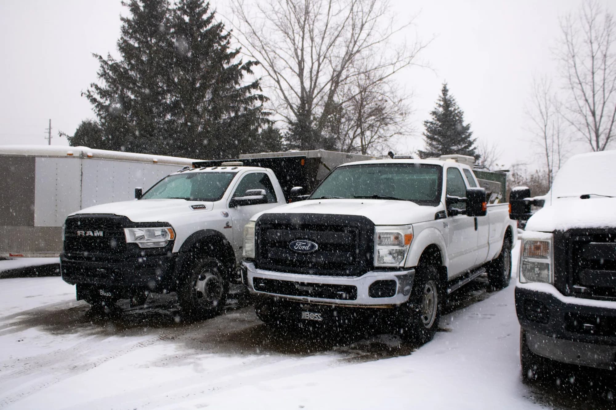 Row of white work pickups parked in a snowy lot