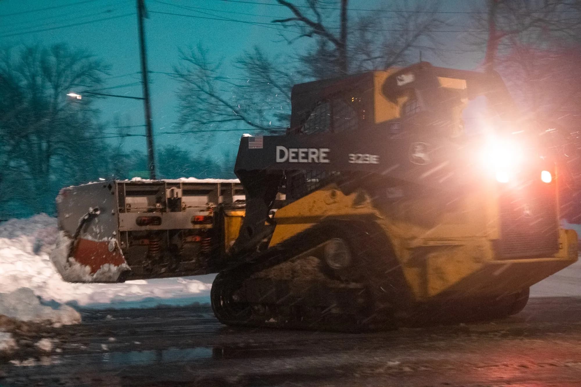 Deere compact track loader pushing snow at night