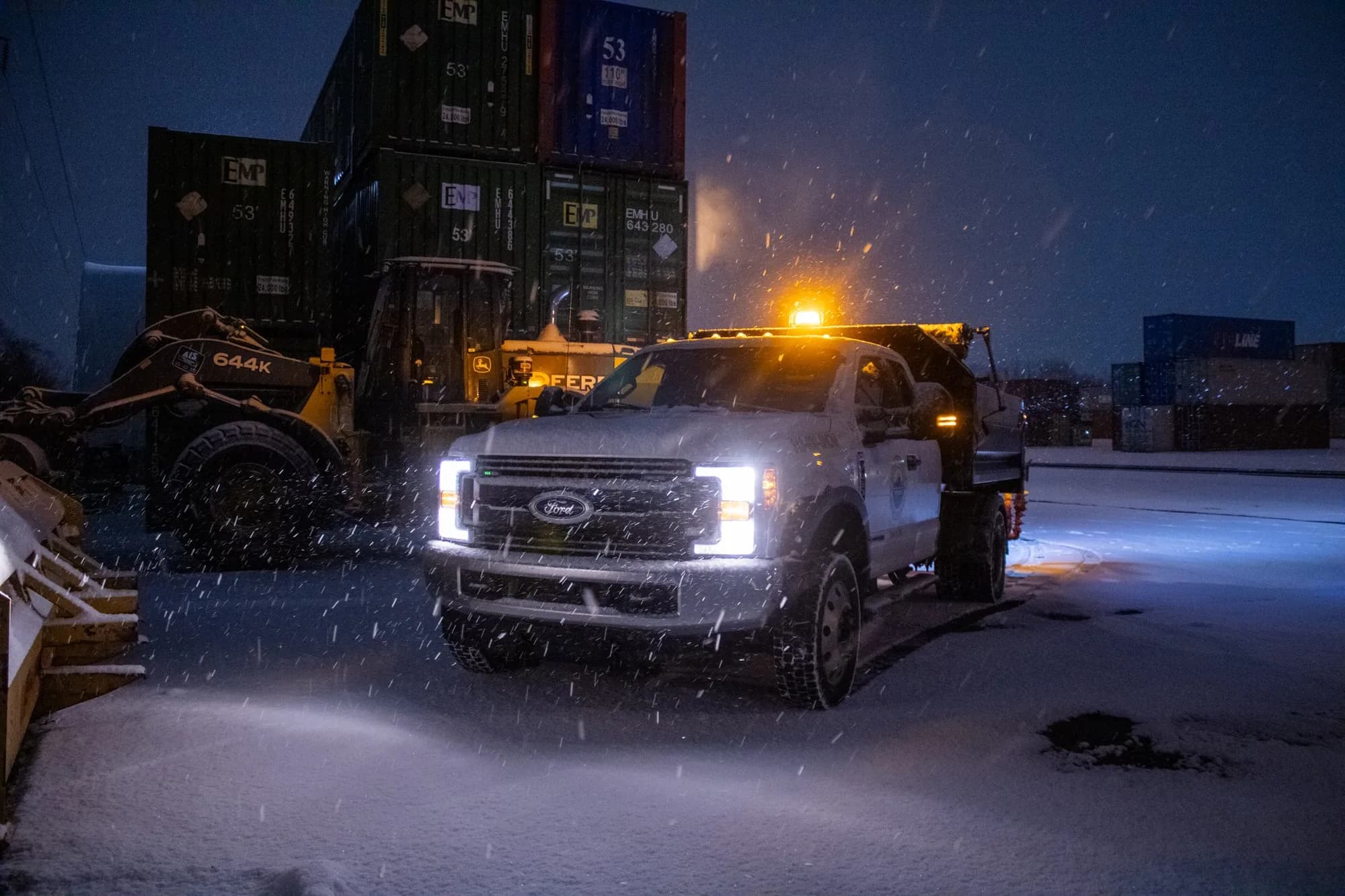Pickup and wheel loader working a lot during a night snowfall