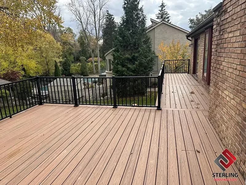 Finished deck with black metal railing behind a brick home