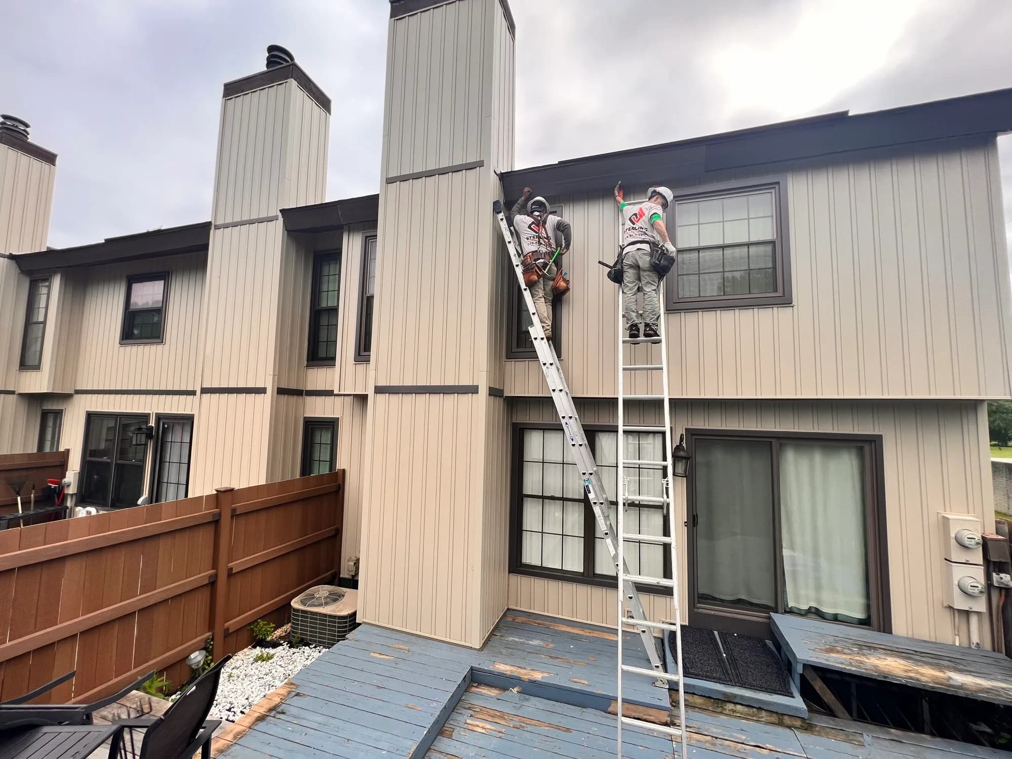 Crew on ladders re-siding a condominium building