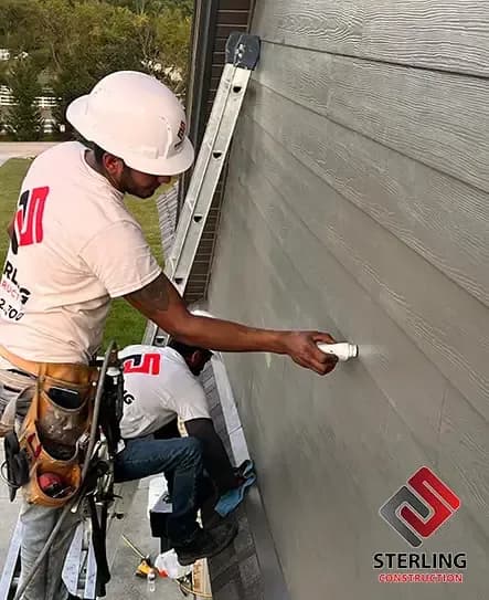 Crew installing gray fiber cement siding