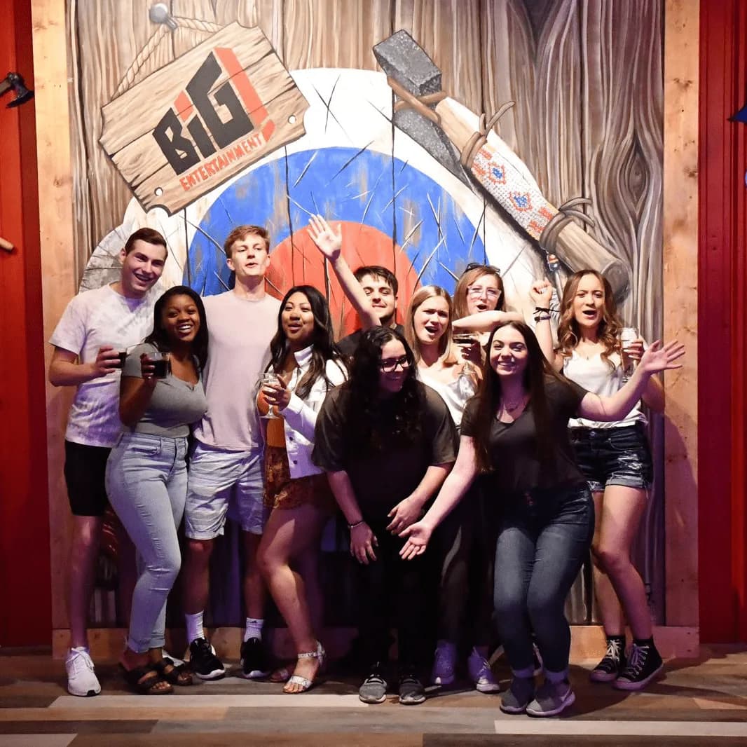 Group posing in front of a BIG axe throwing target