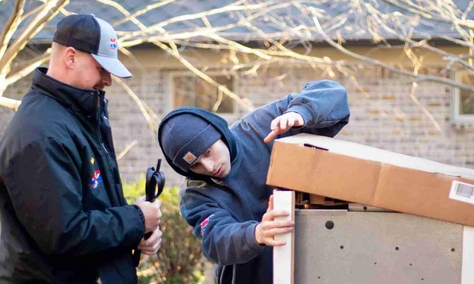 Two technicians unpacking new equipment outside a home