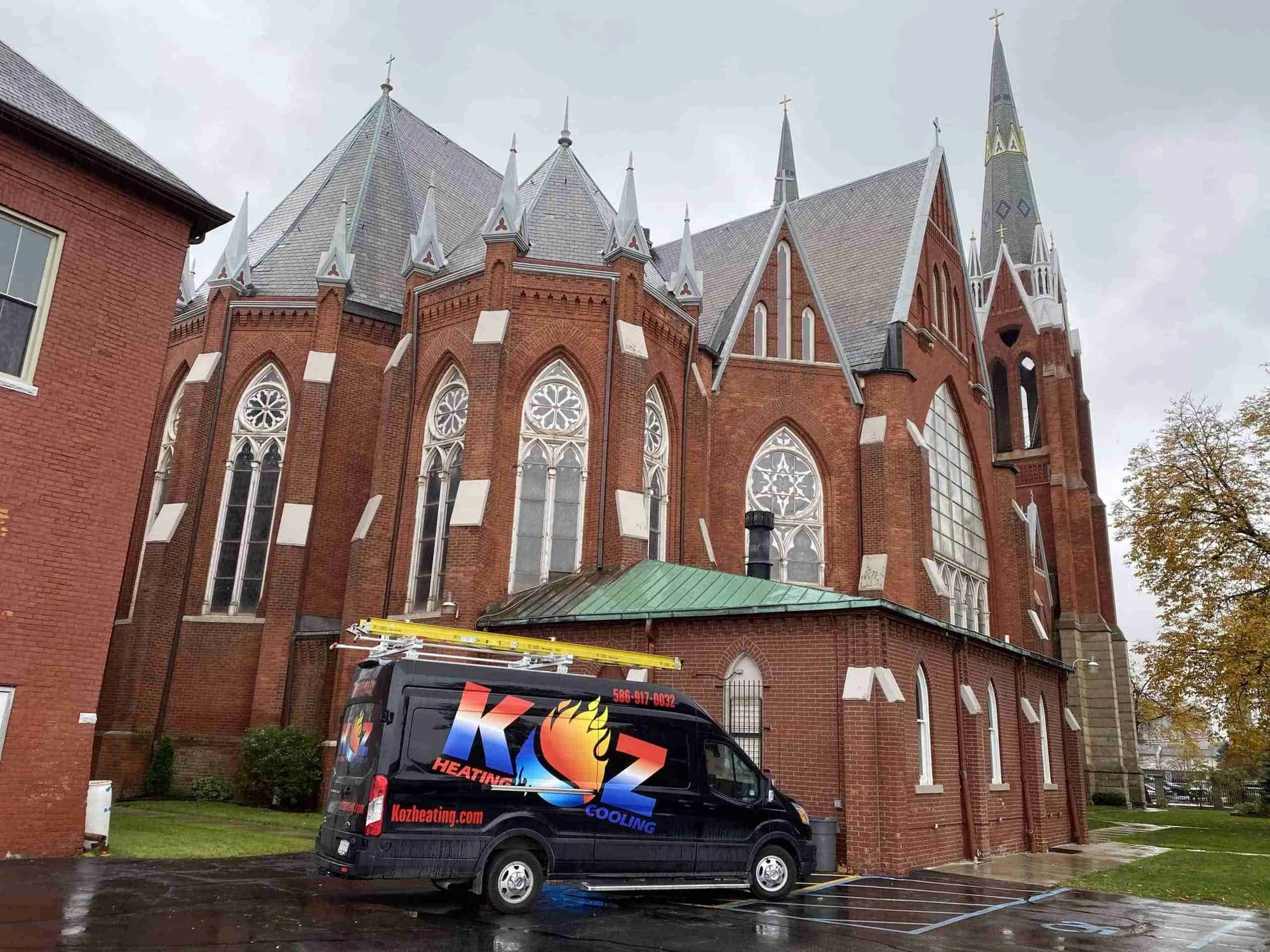 Koz service van parked outside a brick church on a job