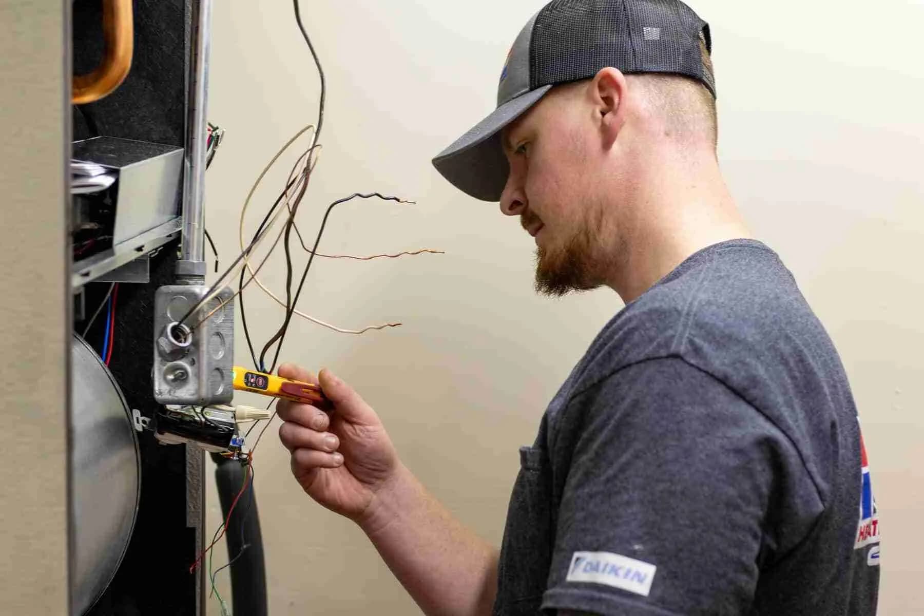 Technician testing furnace wiring with a voltage tester