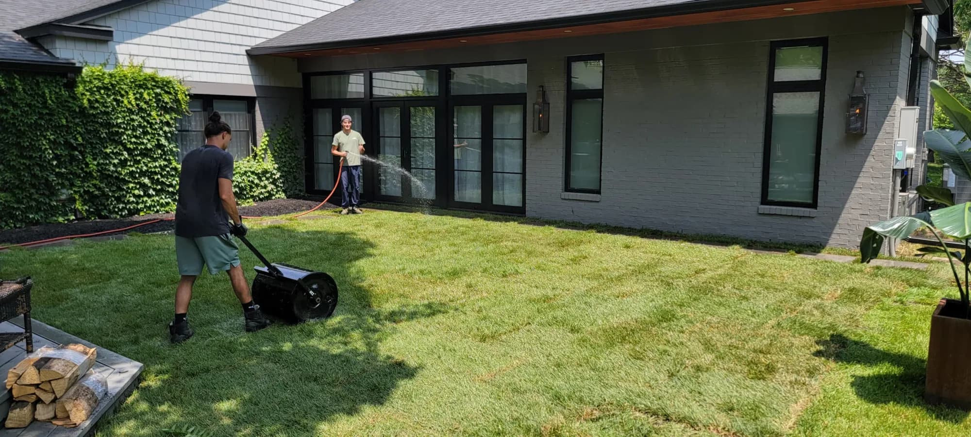 Crew mowing and trimming a lawn behind a home