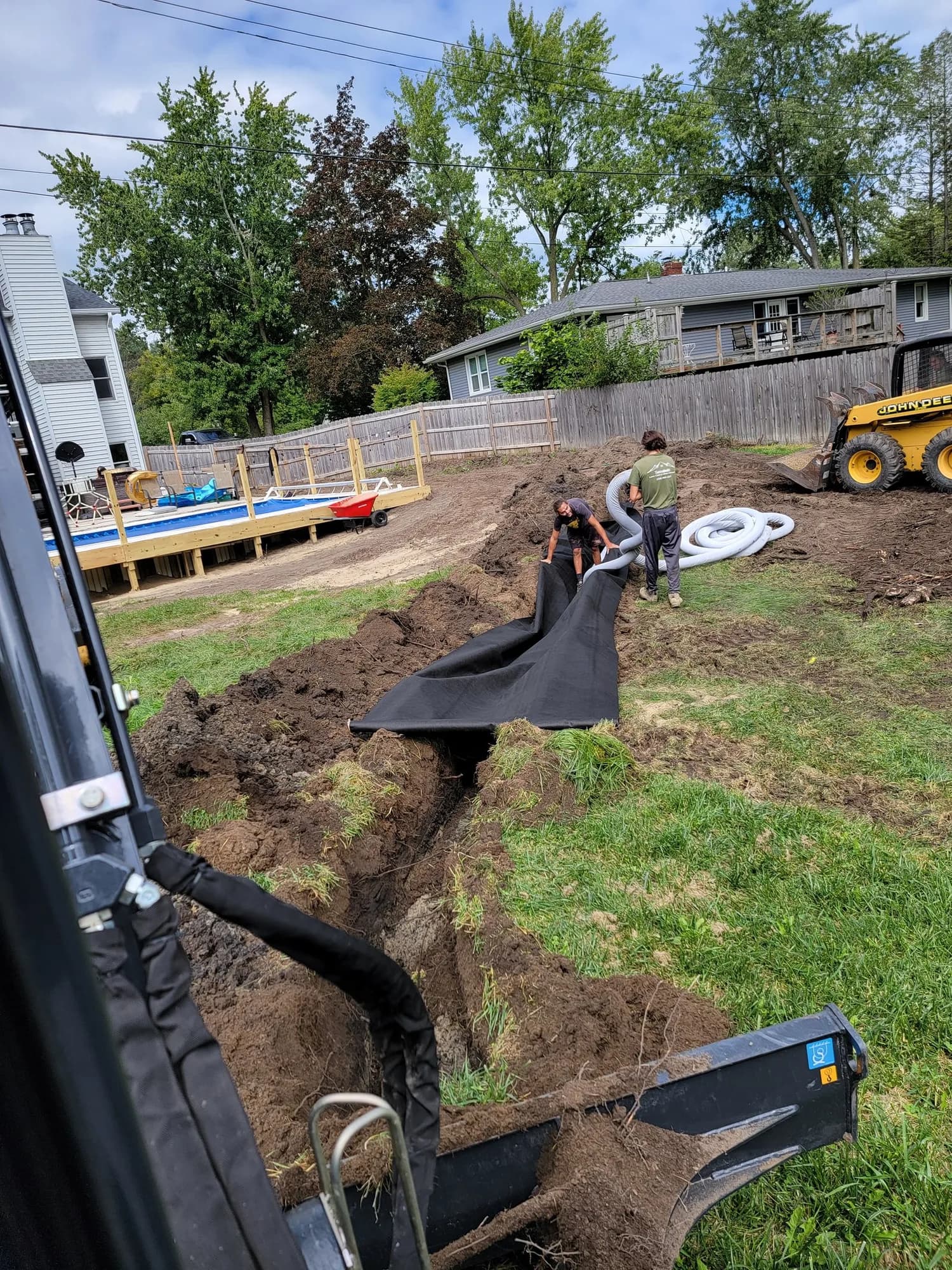 Trench dug for a French drain with pipe and fabric in a residential yard