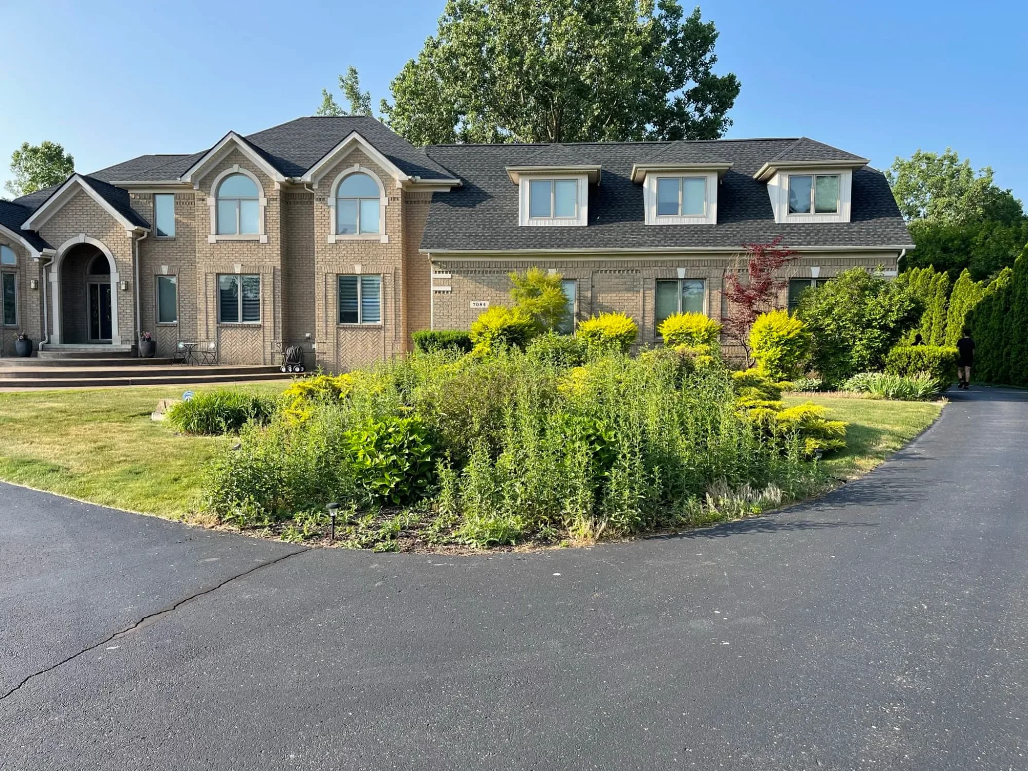 Landscaped island bed along the driveway of a brick home