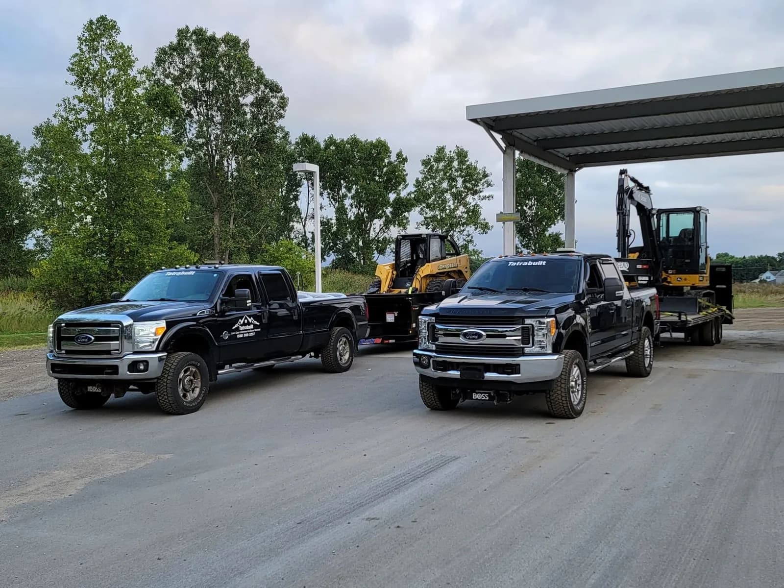 Two work trucks towing a mini excavator and loader on trailers