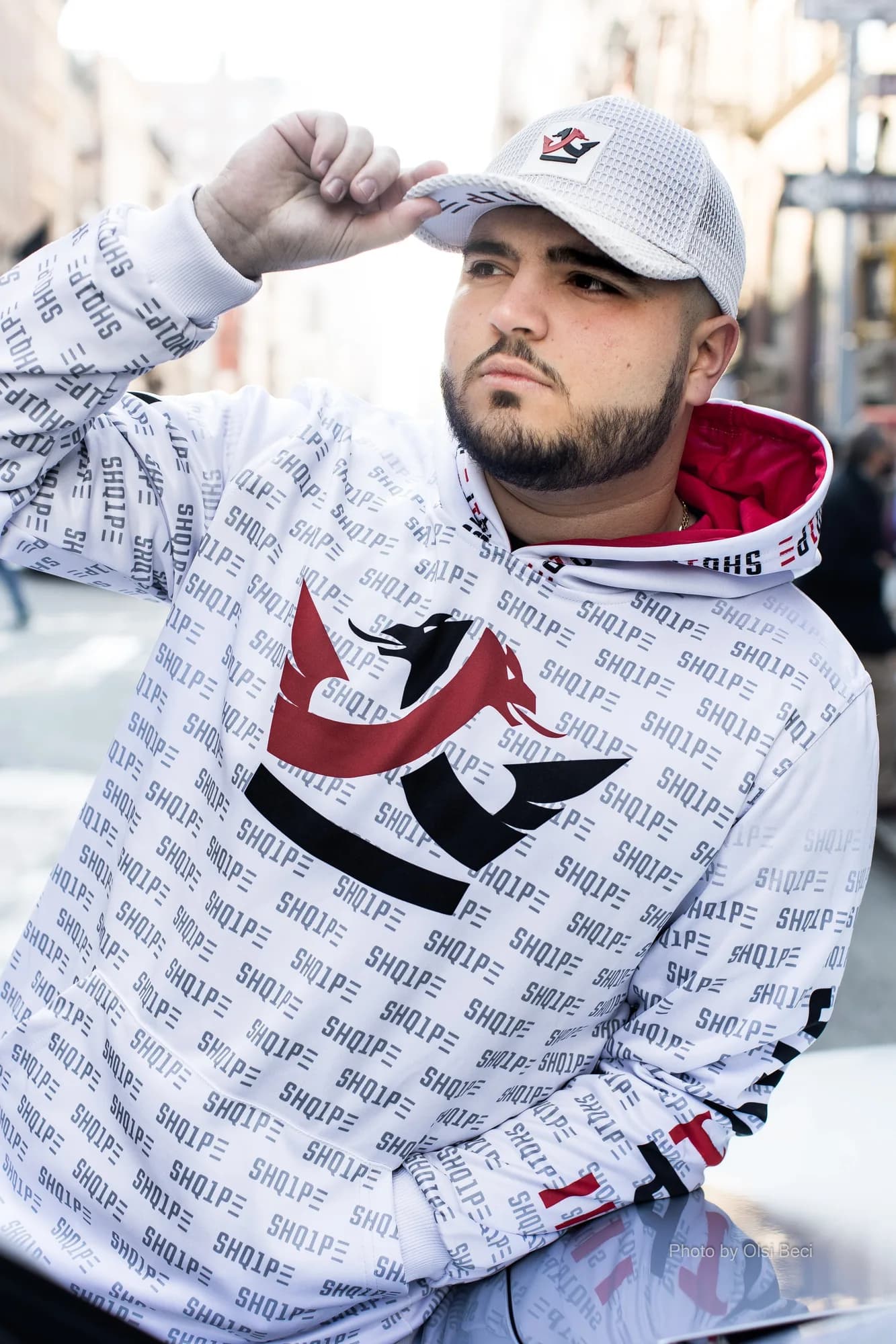 Man in a white Shq1pe logo-print hoodie and cap in Manhattan