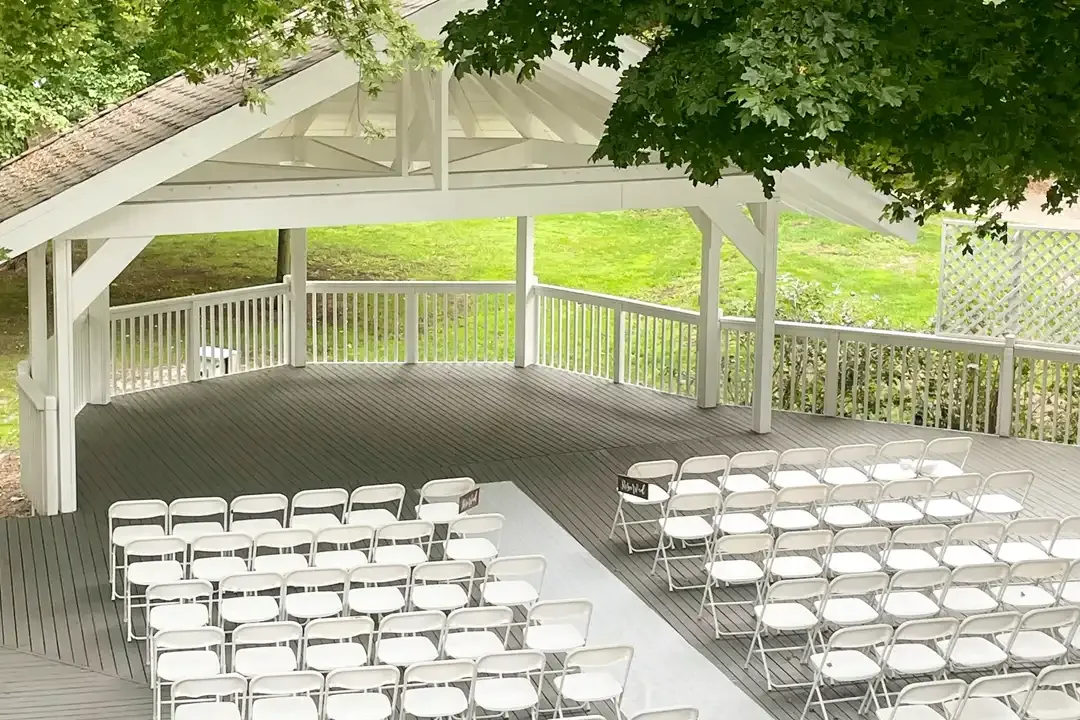 Outdoor ceremony pavilion with rows of white chairs
