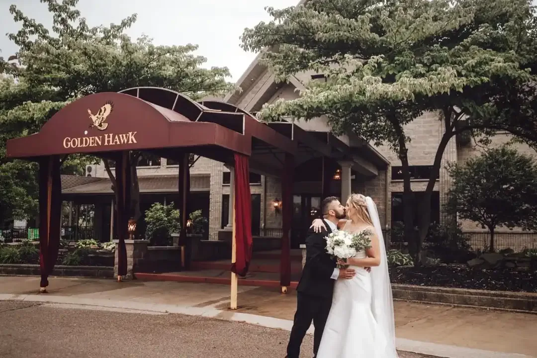 Wedding couple kissing under the Golden Hawk entrance canopy