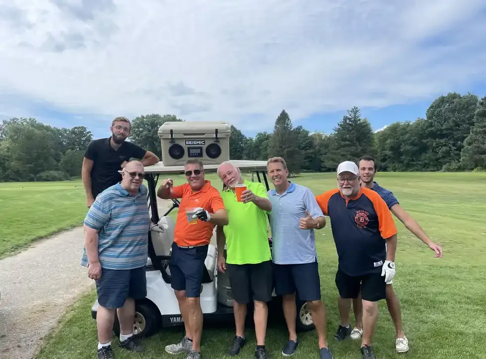 Golfers celebrating beside their cart during an outing