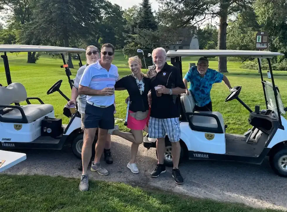Golfers standing beside their carts on the cart path