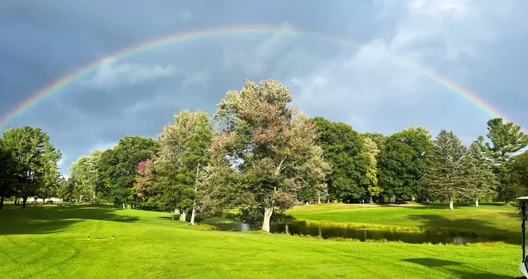 Rainbow over a pond and tree-lined fairway at Bruce Hills
