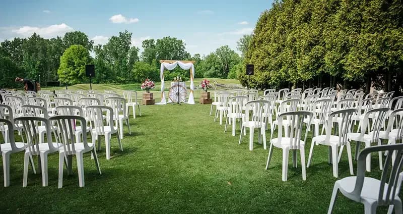 Outdoor ceremony site with rows of white chairs and an arch