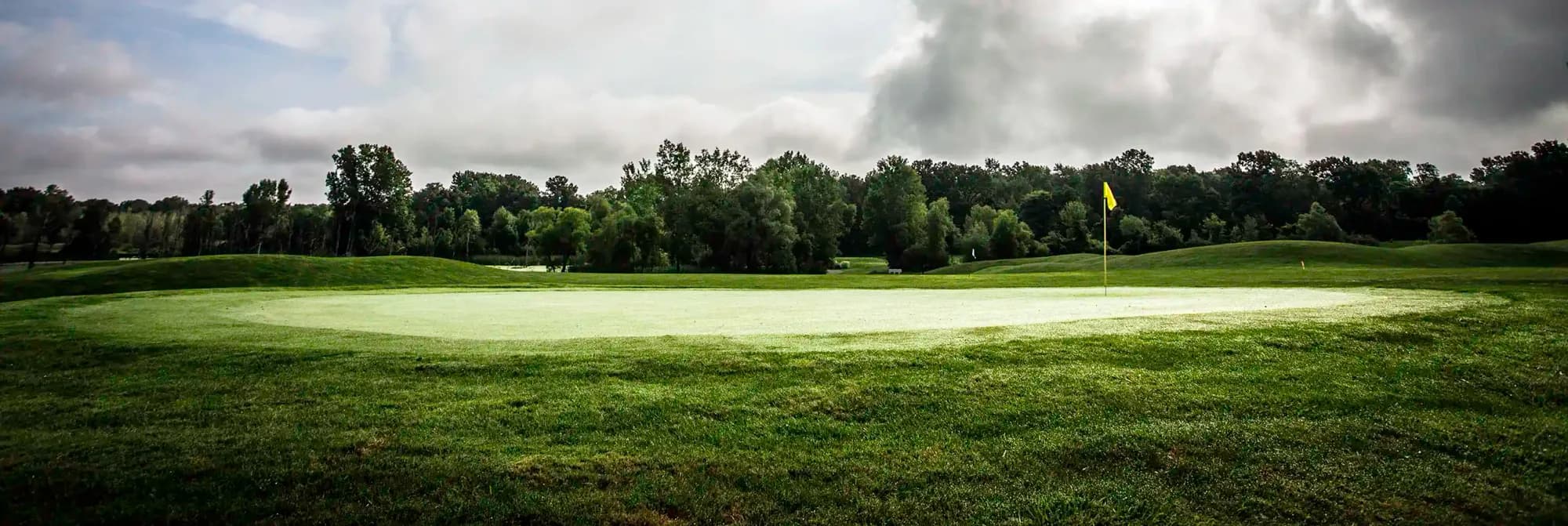 Green and flag under a cloudy sky