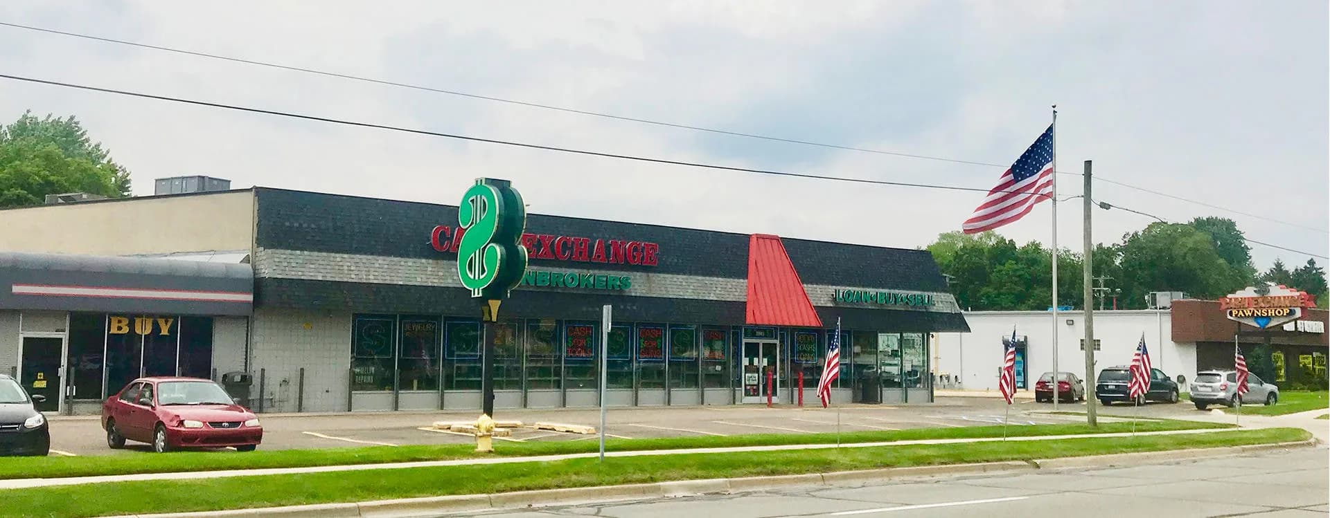 The Cash Exchange Pawnbrokers storefront on Gratiot Avenue with its green dollar-sign sign and American flags