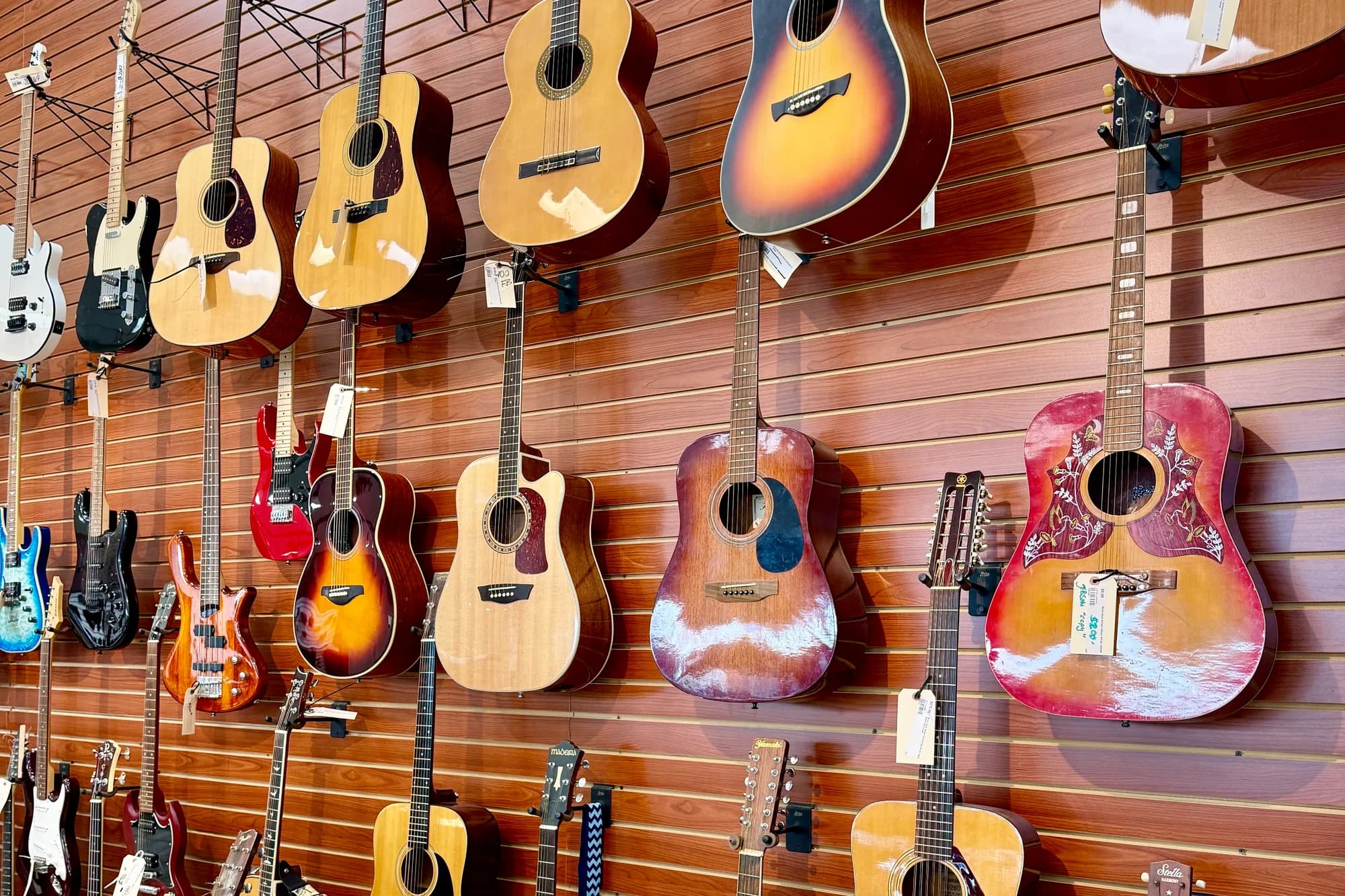Acoustic and electric guitars hanging on the store's slatwall